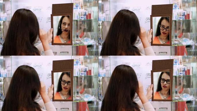 年轻女子在眼镜店的镜子里检查她的新眼镜。眼镜店戴眼镜的年轻女子。眼镜店戴眼镜的美女