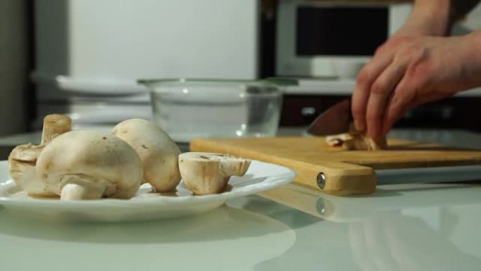 男厨师用手在木板上切新鲜蘑菇