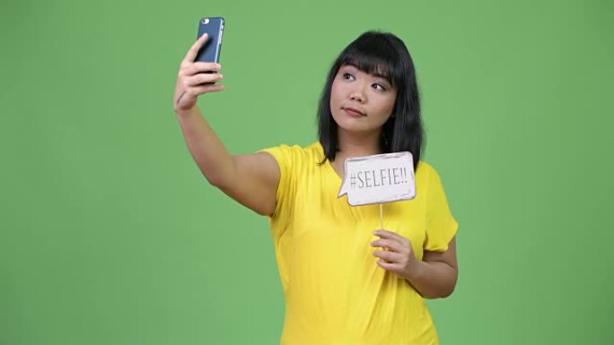 美丽快乐的亚洲女人用纸质标志自拍
