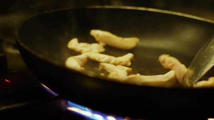 餐厅厨房的厨师在炉灶用锅煮鸡肉餐