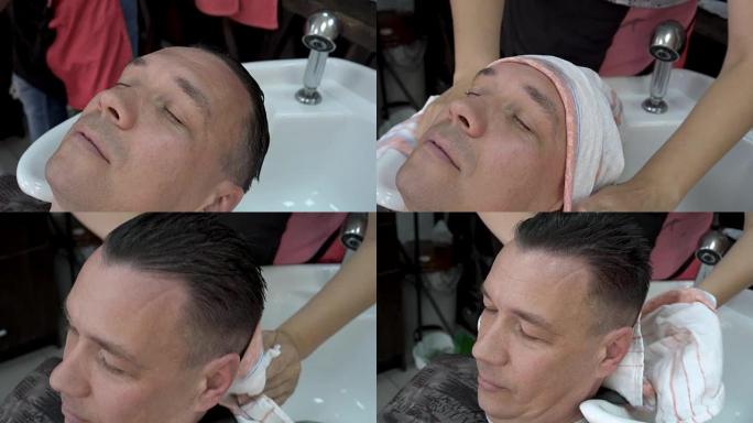 理发师洗漱后在水疗中心用毛巾擦拭男人的头。头发护理。特写，高度细节。
