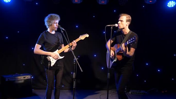 音乐会摇滚乐队与两位电吉他歌手一起在舞台上表演。音乐录影带庞克、重金属或摇滚乐团。两个男人的慢动作乐