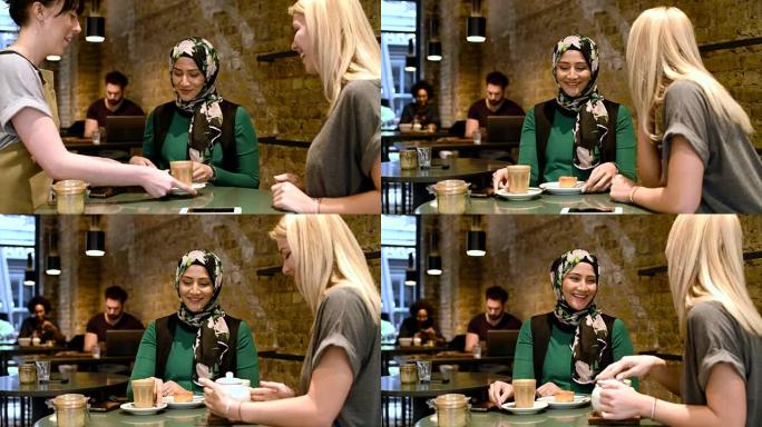 两个女人在咖啡店里用热饮和食物聊天