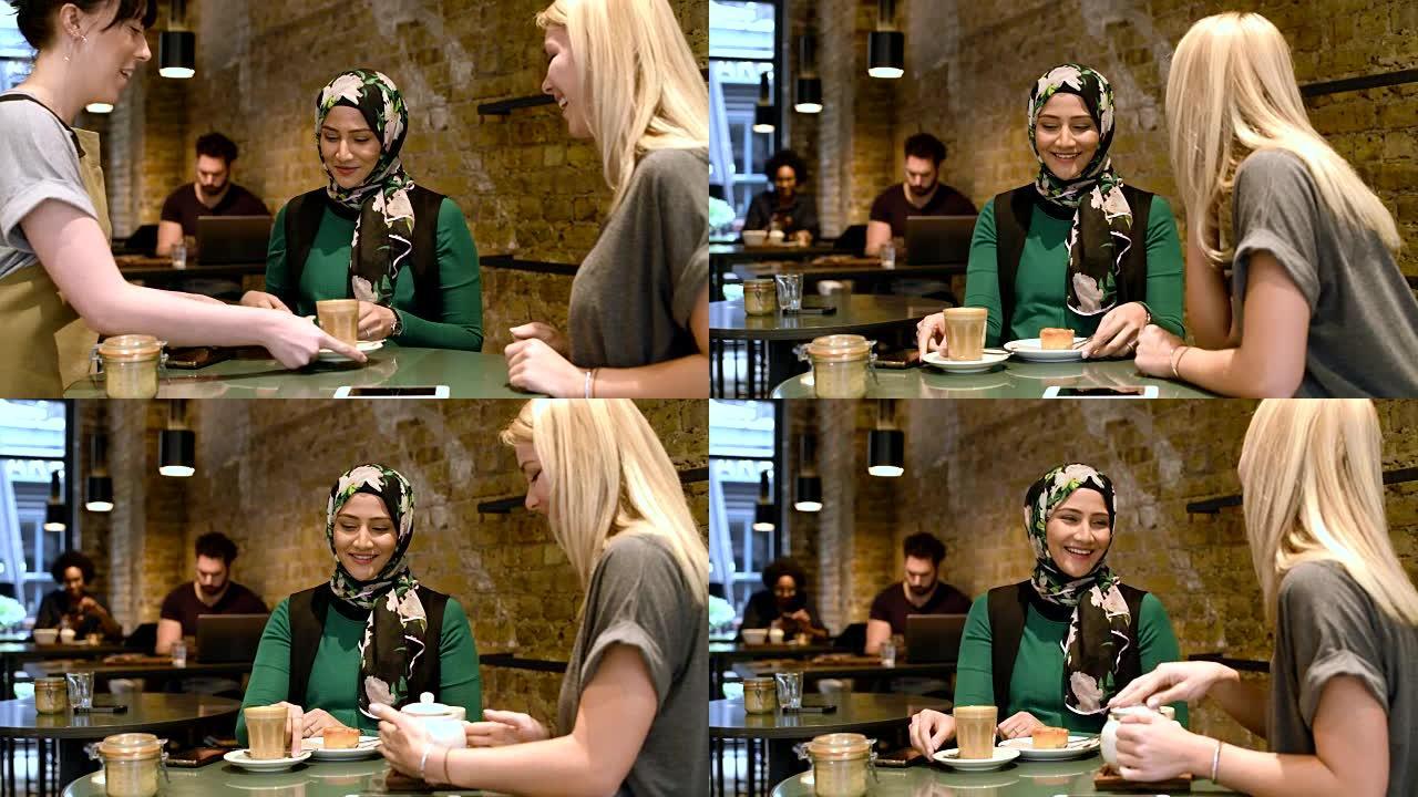 两个女人在咖啡店里用热饮和食物聊天