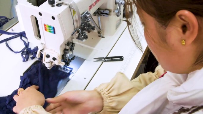 工人在缝纫机前缝制 工人在桌子前裁剪布料 一个女工人在机器前缝制