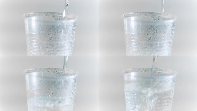 纯净的淡水滴入玻璃杯或塑料杯中关闭，健康的饮料概念