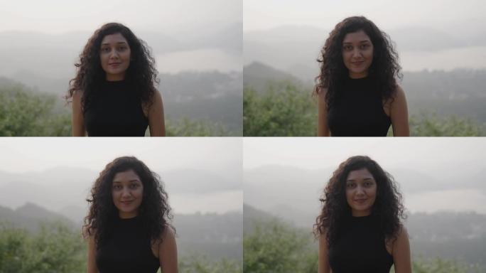 印度女孩微笑着站在山顶享受。