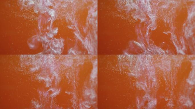橙色和白色闪光在水中旋转和混合背景