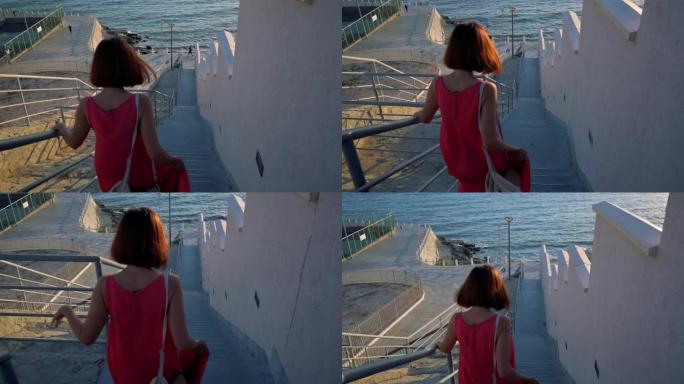 穿着红色连衣裙的女人走下楼梯去波罗的海。女人对大自然印象深刻。4k镜头UHD 3840x2160