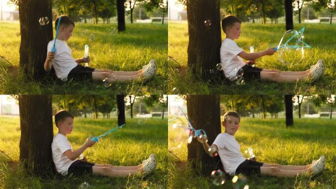 儿童男孩吹肥皂泡，在夕阳下在公园玩耍。孩子在夏天的花园里玩肥皂泡。快乐童年理念