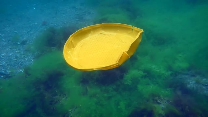 海洋的塑料污染: 塑料一次性盘子慢慢沉入海底。