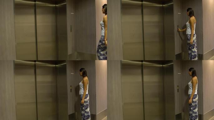 一名妇女接近电梯并按下呼叫按钮