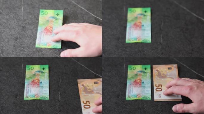一名男子将50欧元的钞票放在50法郎的钞票旁边，因为它们目前的价值大致相同。