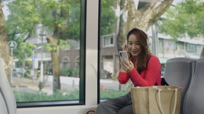 亚洲女性在地铁列车中使用智能手机，在耳机中听音乐音乐应用程序找到最喜欢的配乐歌手歌曲