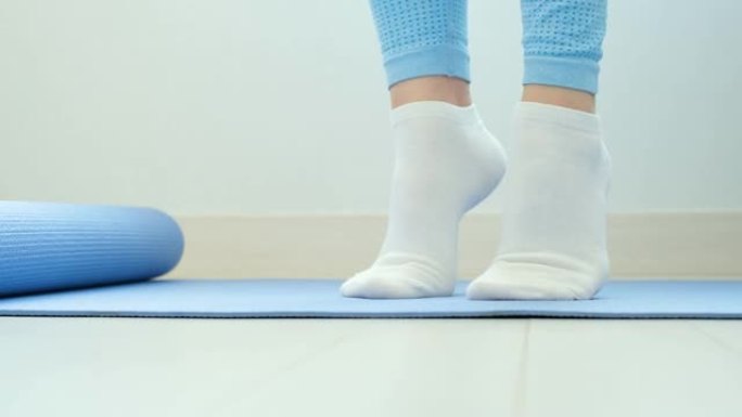 女性腿部做练习提举脚趾特写蓝色背景，前视图。