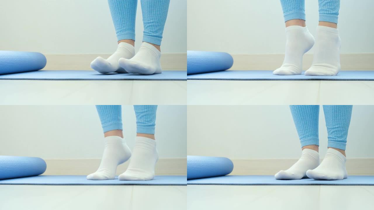 女性腿部做练习提举脚趾特写蓝色背景，前视图。