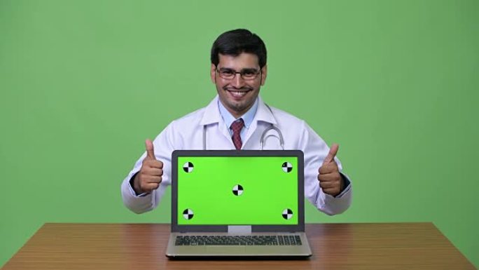 年轻英俊的波斯男子医生展示笔记本电脑