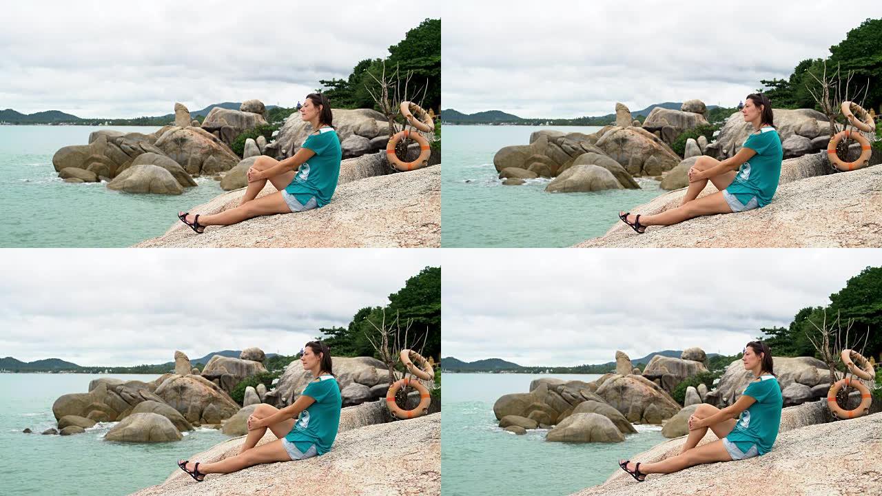女人坐在沙滩上的石头上