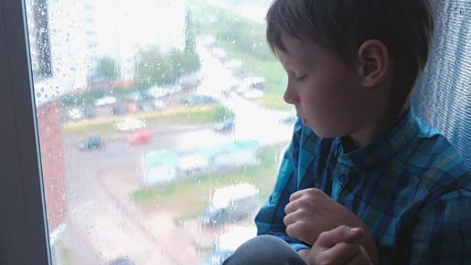 男孩在雨中看着窗外，很悲伤。