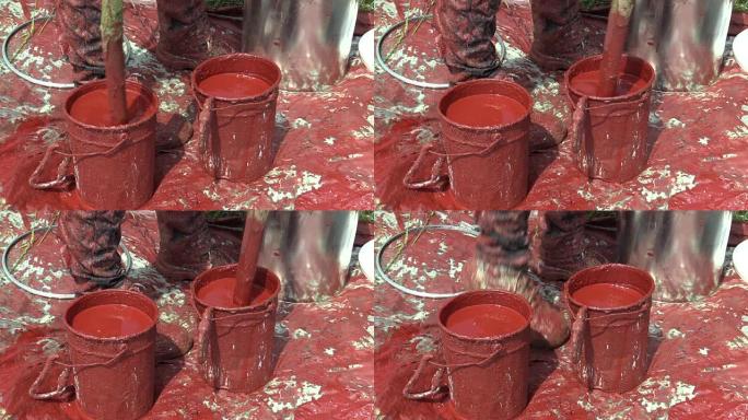 两个合成红色合成漆桶，用于高压电杆铺设引导电线，油漆一根旧钢柱，工人进行专业的油漆稀薄和混合