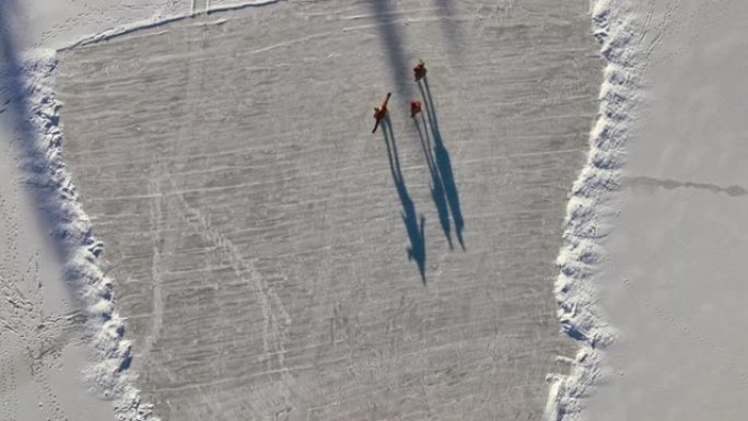空中三人在阳光下在冰冻的湖面上滑冰