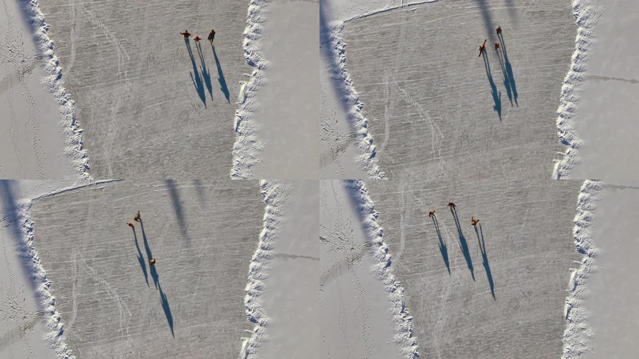 空中三人在阳光下在冰冻的湖面上滑冰