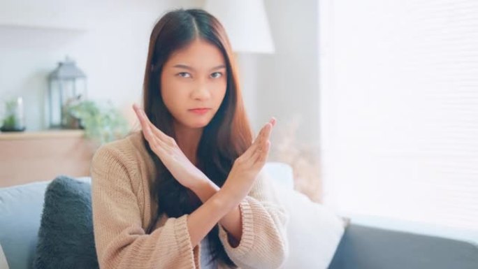 年轻的亚洲女子展示禁止标志，交叉双臂，做出拒绝的手势，消极摇头，不满严重，女性说不拒绝，做出停止的手