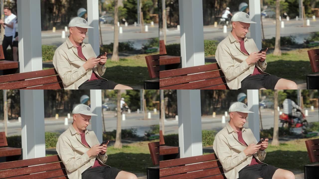 一个年轻人坐在长椅上使用电话。