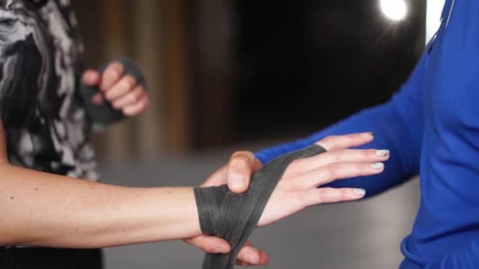 教练用保护带包裹高加索女性拳击手的手。教练帮助女人在战斗前戴上保护性绷带。coach的特写镜头帮助乐