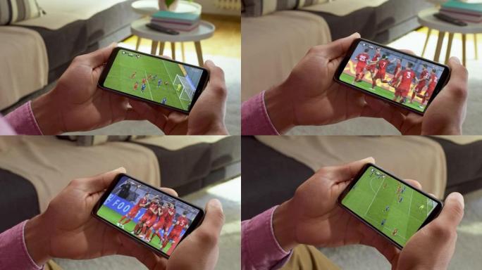 男子坐在沙发上，用智能手机观看足球比赛