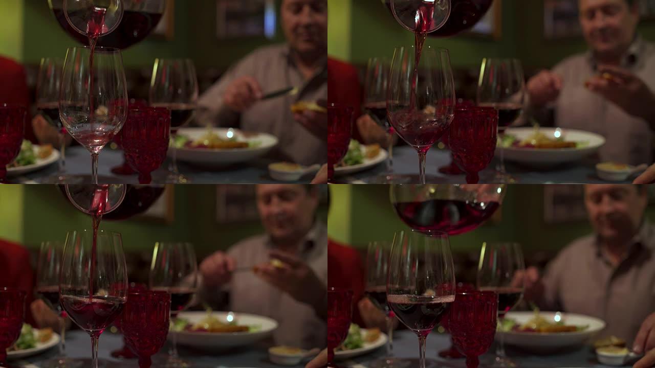 服务员把酒水倒入酒杯中。人们坐在餐桌旁吃饭