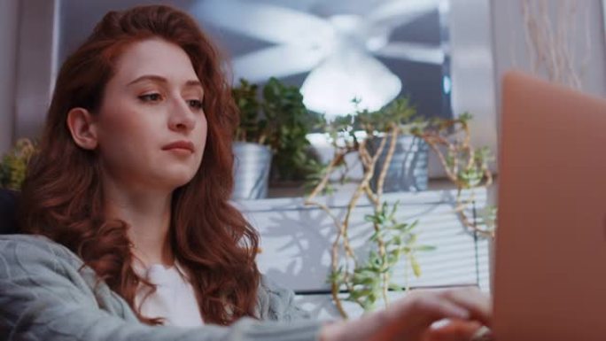 一位年轻美丽的白人妇女正在家里用笔记本电脑工作-令人愉悦的中性表情