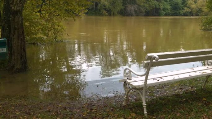 水位上升的泥泞河边缘的白色公园长椅