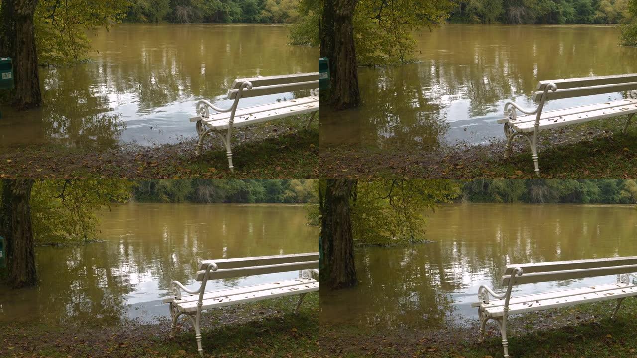 水位上升的泥泞河边缘的白色公园长椅