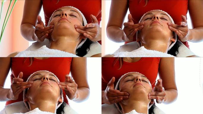 迷人的黑发女人从美丽的金发治疗师那里得到面部按摩