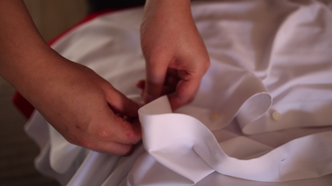 预备婚礼新郎双手系扣子穿白色衬衣结婚服饰