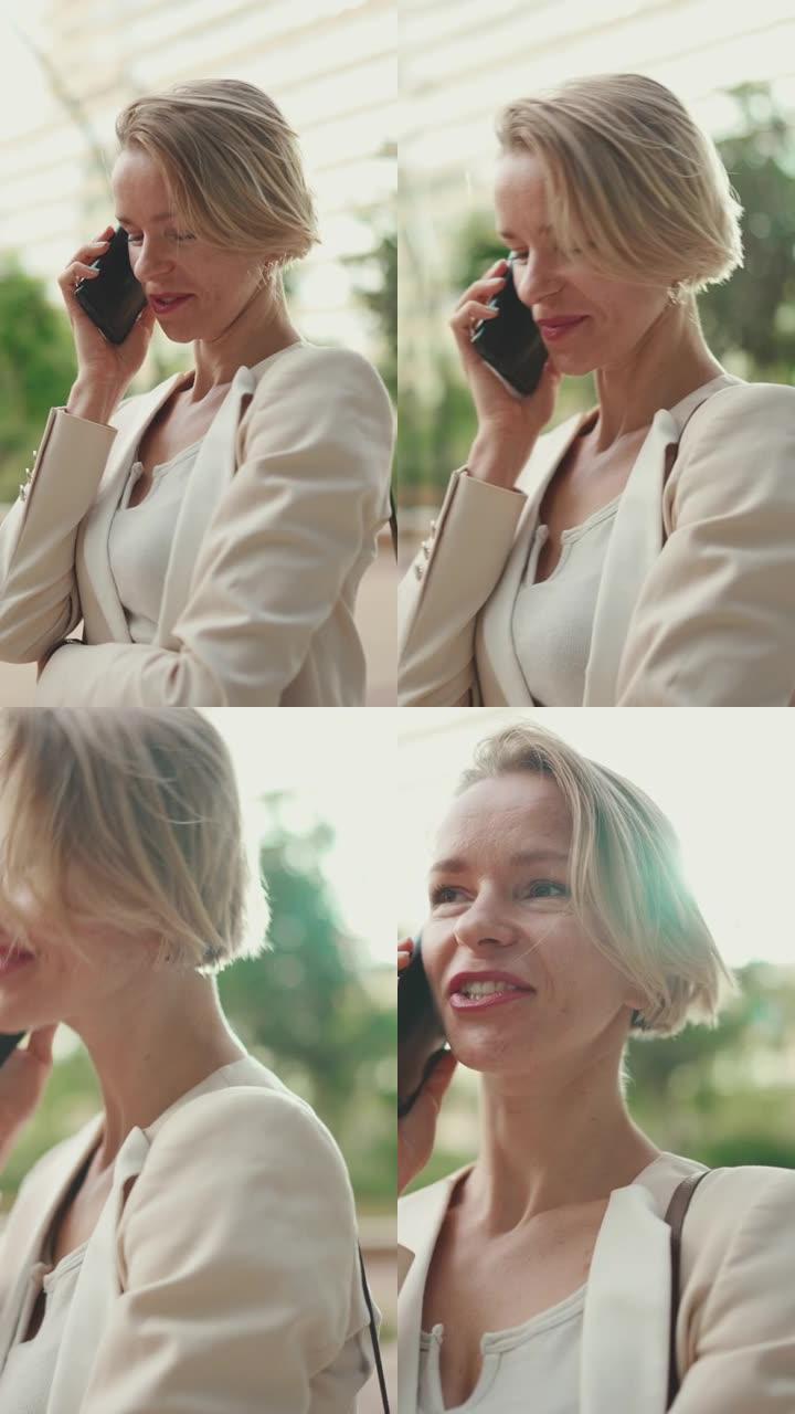 垂直视频: 金发碧眼的快乐女商人在手机上聊天，划算，成功