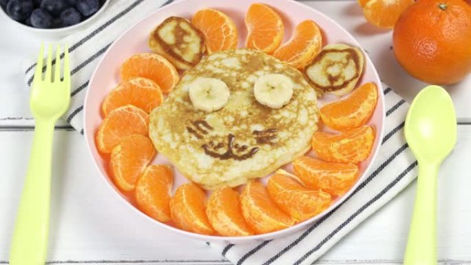 以狮子脸的形式提供薄煎饼和水果的儿童早餐