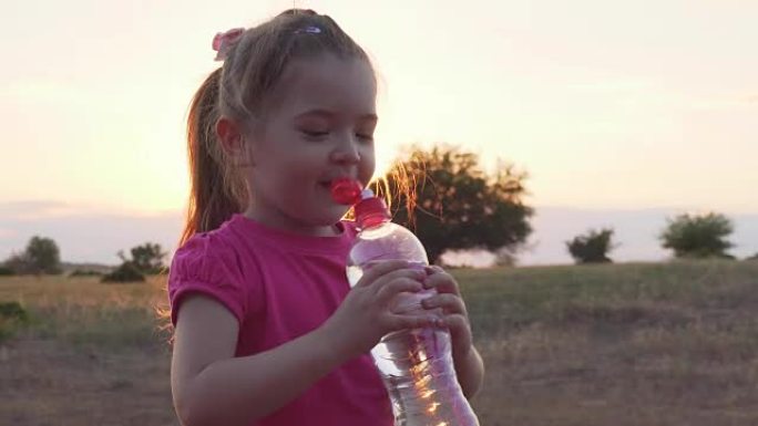 小女孩在日落时用塑料瓶喝水