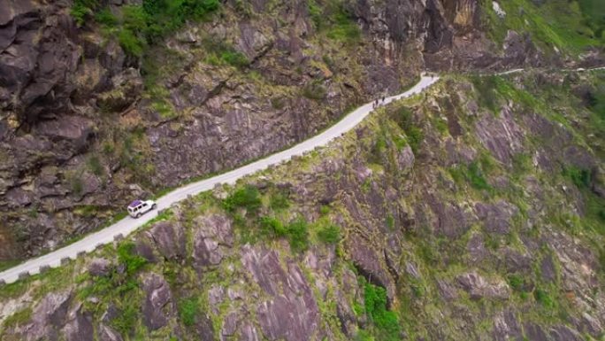 空中SUV沿着河的峡谷在狭窄的道路上行驶