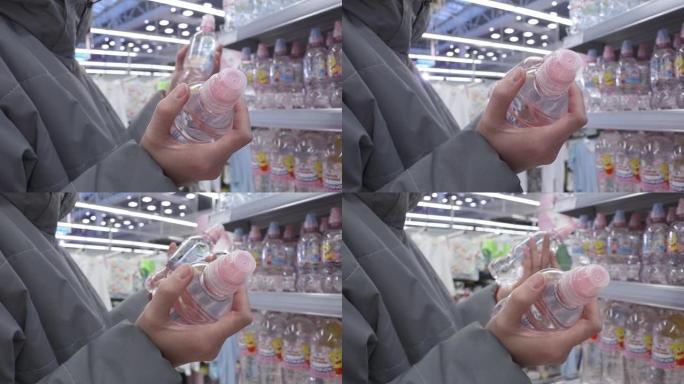 一名妇女正在挑选超市货架上的一瓶矿泉水或饮料。