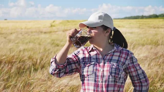 女农民在大麦田里喝黑啤酒