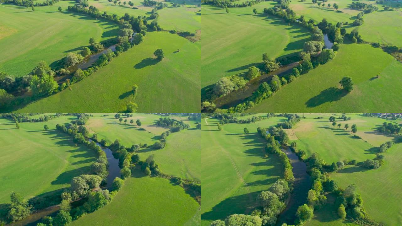 空中: 蜿蜒的河流，被郁郁葱葱的绿树环绕，蜿蜒穿过田野