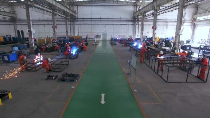 一台机械设备正在高速运转 工厂鸟瞰图 三个穿橙色衣服的工人在讨论工作方法