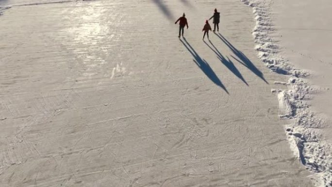三口之家上方的天线在冰冻的湖上滑冰