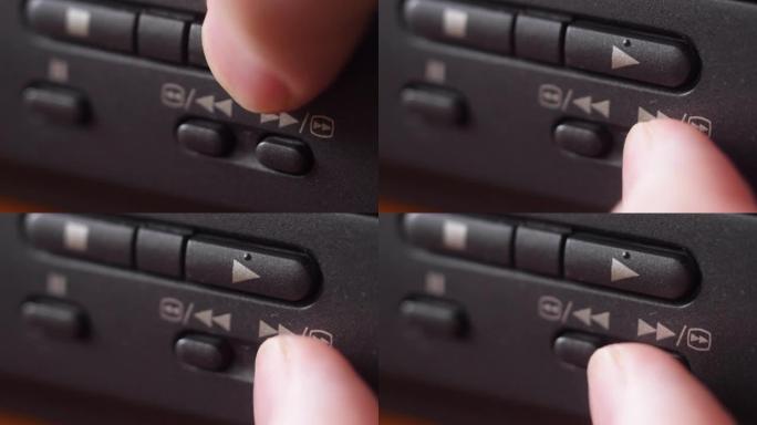 极端特写手指按下录像机面板上的播放和快进按钮。在家庭设备上观看和快速转发电影