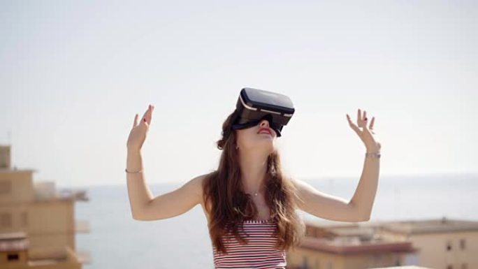 美丽的年轻女子在虚拟现实眼镜玩游戏。未来就是现在。女性用现代虚拟现实眼镜触摸东西。技术与创新