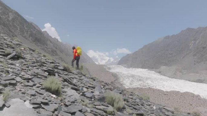 带着背包在山上攀登的女性徒步旅行者的空中无人机视图。