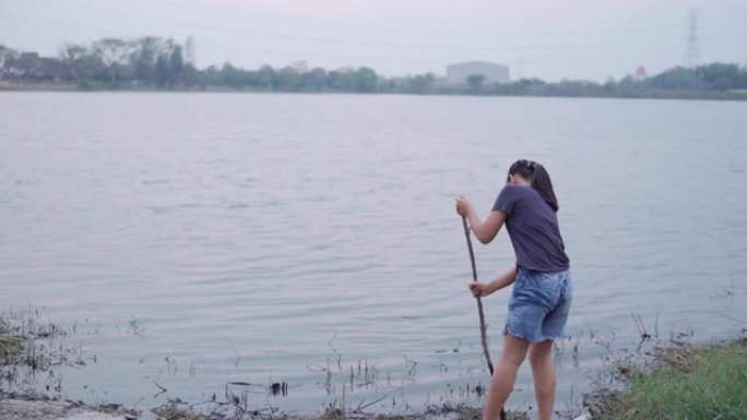 亚洲女孩在大自然中休息和享受，在湖边玩泥