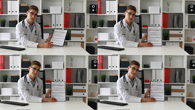 年轻的医生展示纸张并看着相机